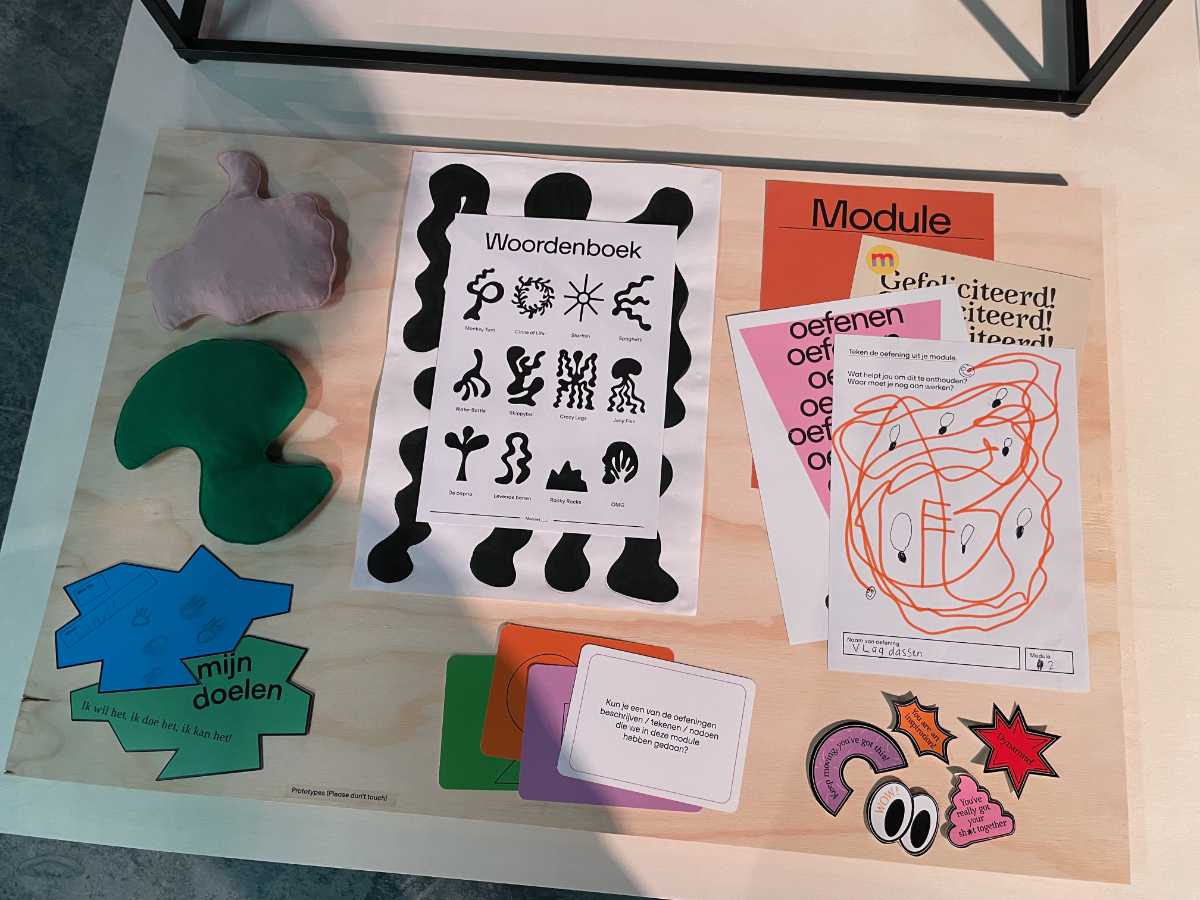 Viele bunte Papiere in verschiedenen Größen liegen auf einem Holztisch. Einige sind Arbeitsunterlagen. Auf Ihnen steht auf Niederländisch „Woordenboek“ oder „Module“. Andere dienen als Sticker und Karten für Pinnwände.